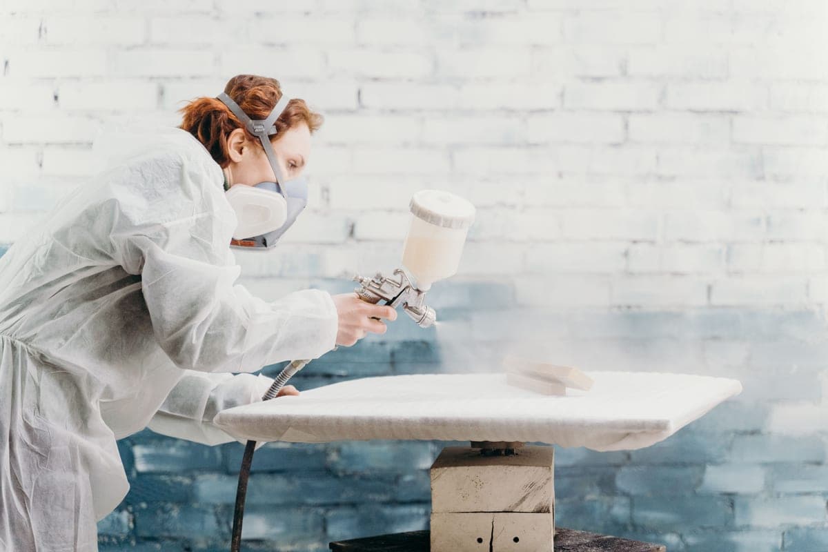 Using a paint sprayer on furniture in a workshop